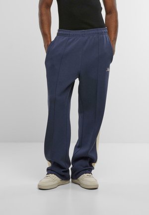 Marineblaue Sweatpants mit hellbeigen Einsatz an den Seiten, elastischem Bund und seitlichen Taschen, aus einem weichen, strukturierten Stoff.
