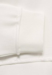 Bílý manžetový svršek z bavlny s ribovanou strukturou a čistým, zesíleným švem. Hladká tkanina s minimálními viditelnými švy.