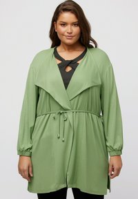 Grüne Wickeljacke mit langen Ärmeln, tailliertem Schnitt und einem drapierten Kragen. Sie verfügt über einen strukturierten Stoff und seitliche Taschen für Funktionalität.