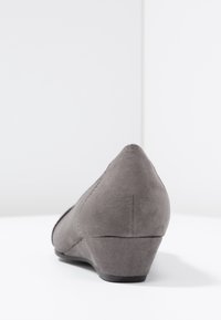 Scarpe con tacco a cuneo in suede grigio, caratterizzate da una punta affusolata e un tacco basso, con una superficie liscia e dettagli di cucitura minimi.