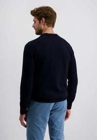 Maritimer, gestrickter Pullover mit gerippten Bündchen und Saum, ausgestattet mit einem Rundhalsausschnitt und einer glatten Textur, kombiniert mit hellblauen Cordhosen.