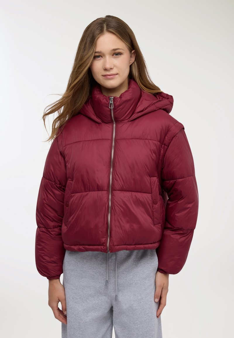Giacca imbottita bordeaux con colletto alto e cappuccio, dotata di chiusura con cerniera e due grandi tasche frontali. Tessuto liscio e lucido.