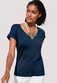 Marineblauwe, kortärmige V-hals T-shirt van zachte stof, met een losse pasvorm en opgerolde mouwen. Gedirigeerd met een gelaagde halsketting.