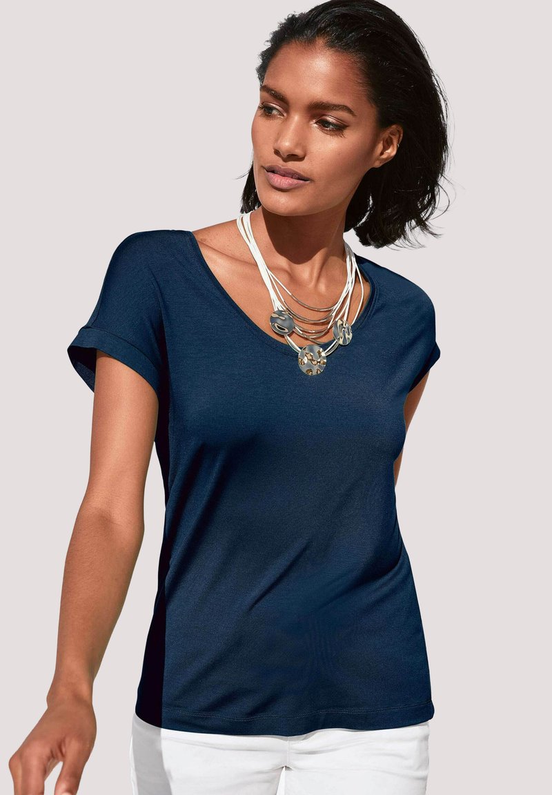Marineblauwe, kortärmige V-hals T-shirt van zachte stof, met een losse pasvorm en opgerolde mouwen. Gedirigeerd met een gelaagde halsketting.