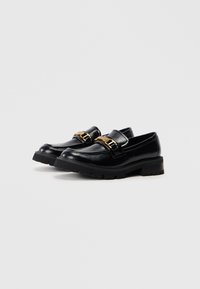Loafers din piele neagră, cu talpă masivă, având un detaliu proeminent cu cataramă aurie și un finisaj neted, concepuți pentru durabilitate.