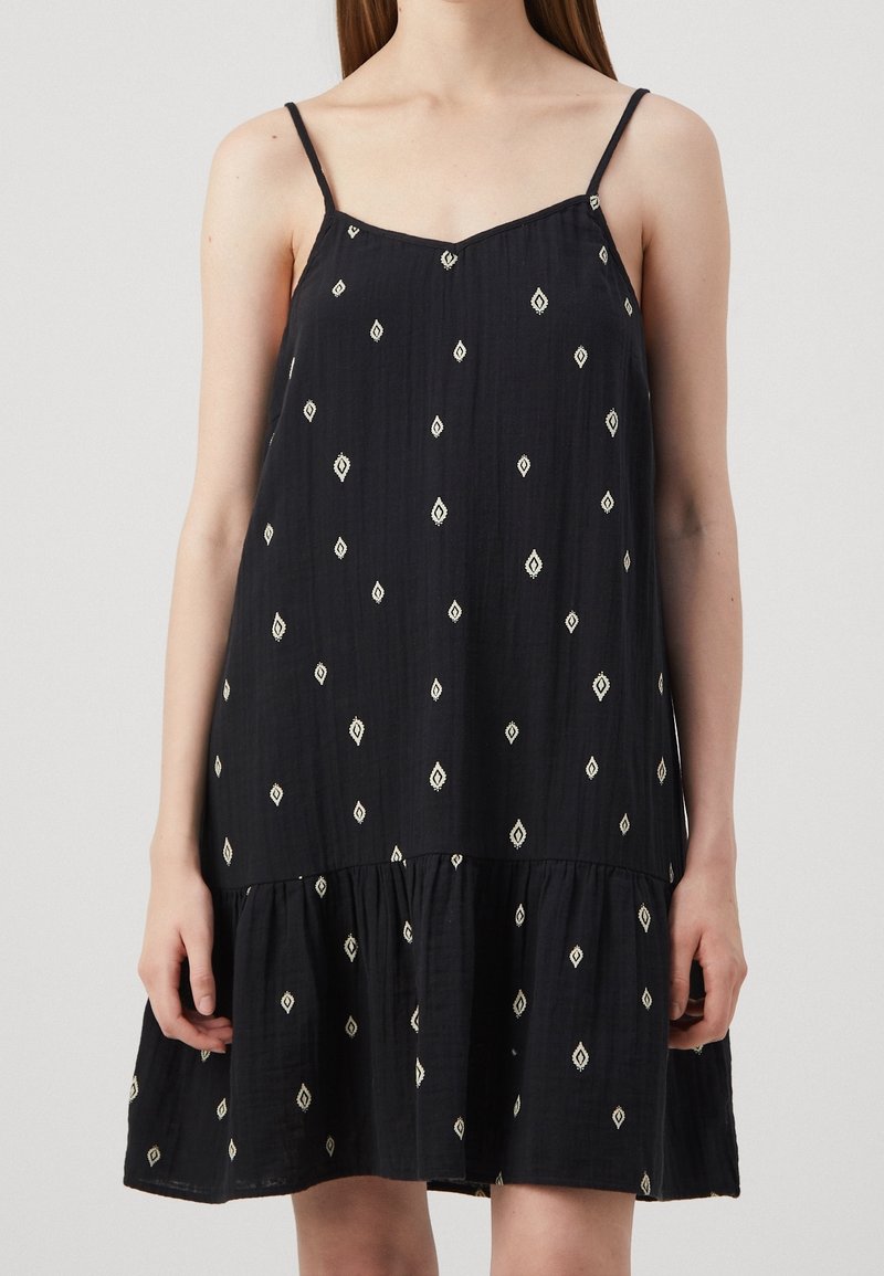 Musta hihaton mekko rentoa istuvuutta, jossa on valkoisia timanttikuvioita ja kerroksellinen helma, valmistettu kevyestä kankaasta.