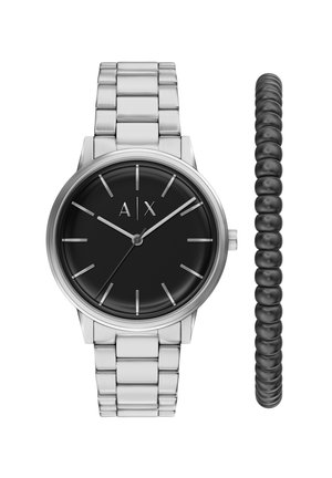 Silberne Metallarmbanduhr mit schwarzem Zifferblatt und silbernen Stundenmarkierungen und Zeigern, neben einem schwarzen Perlen-Stretcharmband.
