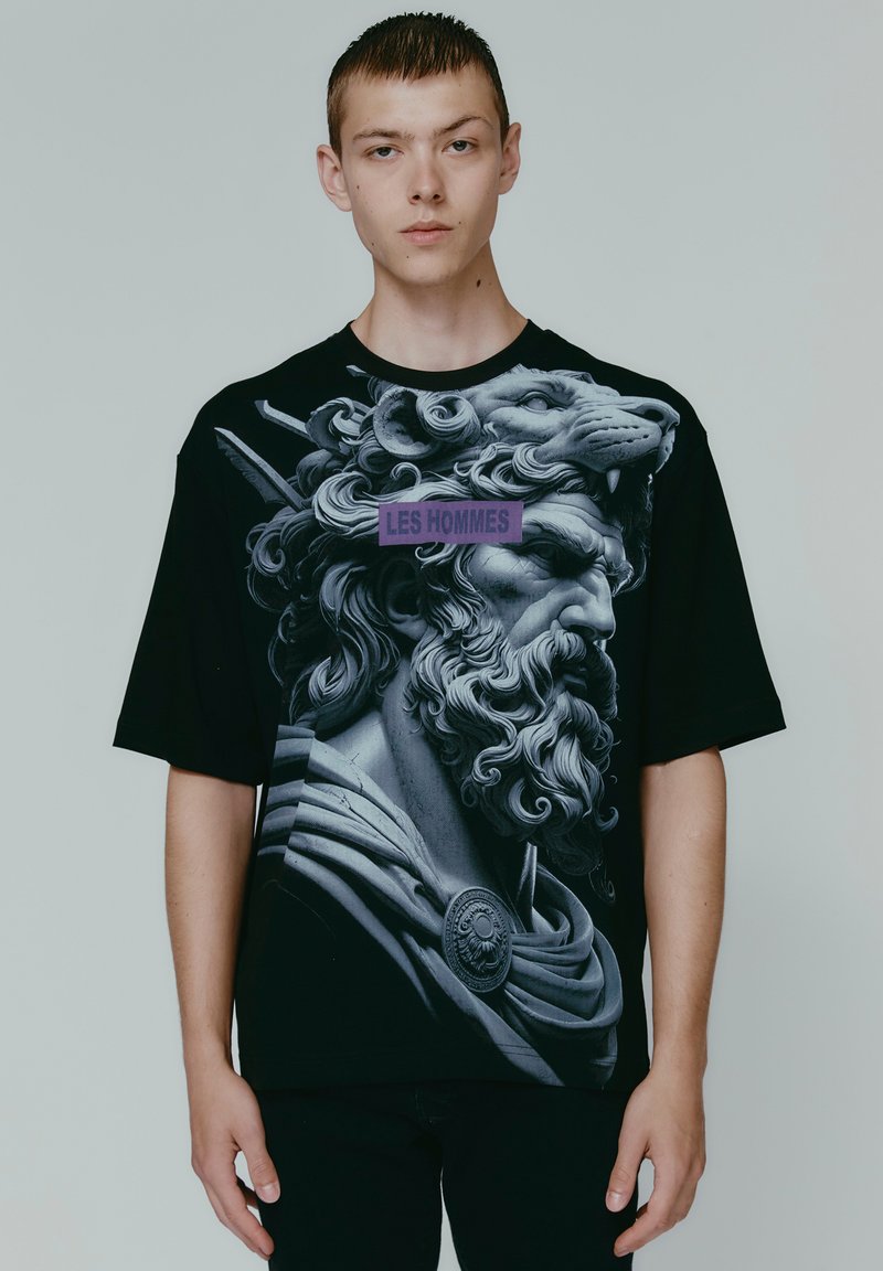 Black t-shirt featuring a large, detailed graphic of a lion-headed figure in gray tones, with "LES HOMMES" text in purple across the chest.