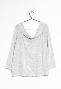 Sølv kortærmet top med cowl neck, der har en tekstureret overflade med pailletter, hænger fra en sort bøjle mod en hvid baggrund.
