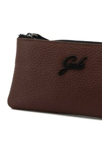 Bustina in pelle marrone con superficie texture, dotata di una zip nera e logo impresso. Forma rettangolare compatta, adatta per la conservazione.