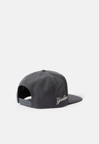 Sivá baseballová čiapka, štruktúrovaný dizajn, plochý okraj, vyšívaný nápis "Yankees" na boku v bielej farbe, nastaviteľný snapback popruh.