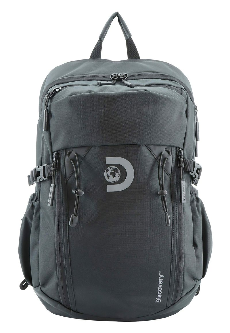 Mochila de tela gris con múltiples compartimentos con cremallera, correas ajustables y un logo circular. Cuenta con bolsillos laterales de malla y costuras resistentes.