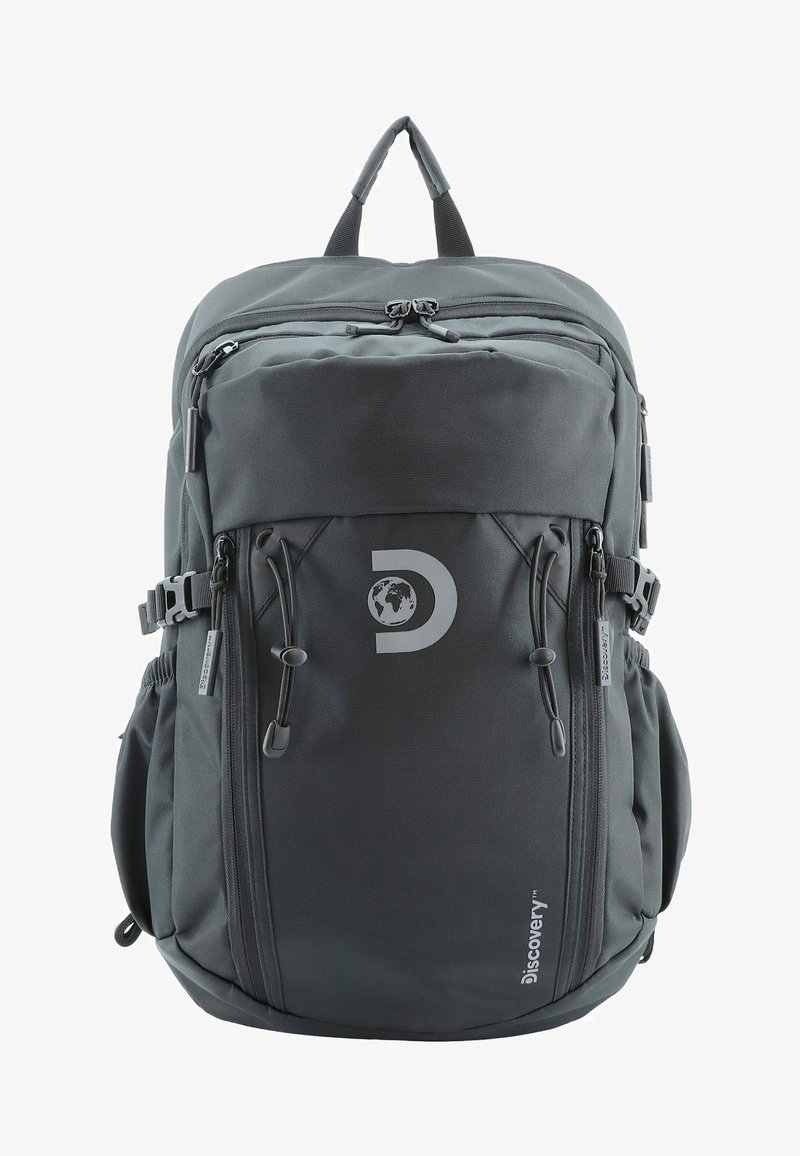 Mochila de tela gris con múltiples compartimentos con cremallera, correas ajustables y un logo circular. Cuenta con bolsillos laterales de malla y costuras resistentes.