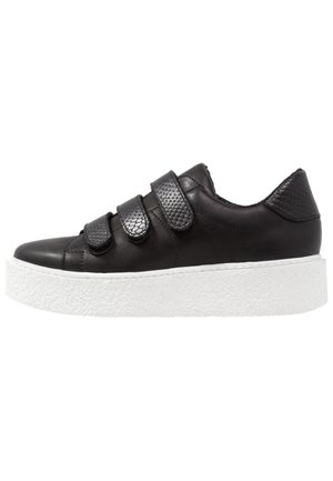 Baskets en cuir noir avec trois sangles velcro, talon texturé et semelle plateforme blanche. Fini lisse avec un minimum de détails de couture.