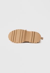 Ταν καουτσούκ σόλα μπότες με βαθιές ραβδώσεις και αυλακιές για πρόσφυση; επίπεδη φτέρνα και λείες άκρες; ελάχιστη σήμανση στο κέντρο.