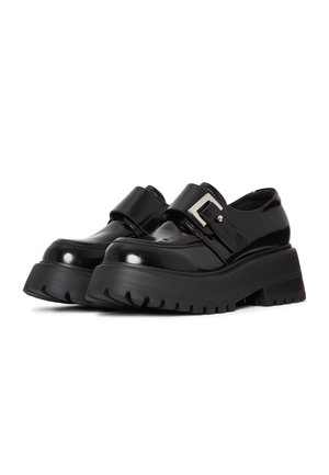 Black patent leather shoes with a chunky black rubber sole, featuring a wide strap with a silver buckle accent. Designed with a rounded toe.