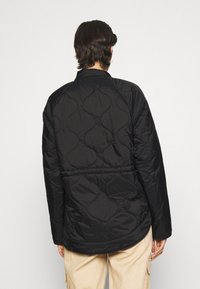 Mustahdil da turi megharqat bir qora yorganchak, toza va porloq to'rtta naqsh bilan qoplangan. Dizaynda keng fit va doira shaklidagi bo'yin mavjud.