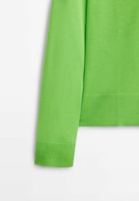 Manche et taille de pull tricoté vert vif avec poignets côtelés sur fond blanc.