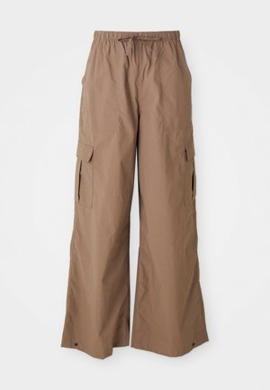 Brune, løstsittende cargo bukser med snor i midjen og sidelommer med klaff, bred ben design, vist mot en hvit bakgrunn.