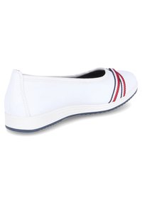 Weiße flache Schuhe mit runder Zehenpartie, ausgestattet mit roten und marineblauen Streifen an der Seite, Gummisohle und gesteppten Details an der Ferse.