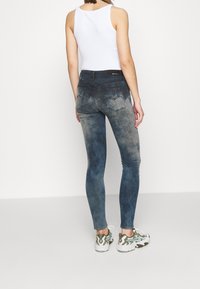 Slitna jeans i blek blå denim med en slät textur, med hög midja och två bakfickor. Matchas med vit linne och sneakers.