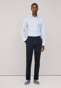 Lichtblauwe geblokte overhemd met knopen, donkerblauwe broek, en blauwe instappers. Zachte stof, slim fit, en casual stijl.