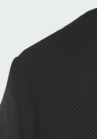 Chemise noire avec un motif texturé et un design en grille. Le tissu semble lisse avec un léger éclat d'un côté.