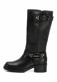 Bota de cuero negra hasta la pantorrilla con tacón bajo y cuadrado, correas con hebilla en la parte superior y en el tobillo, y detalles de remaches metálicos.