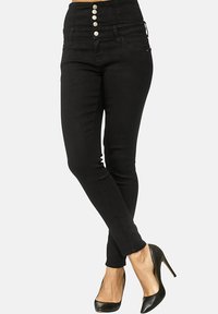 Jeans negros de talle alto con cinco botones en la parte frontal, corte ajustado y tejido de denim suave, combinados con zapatos de tacón negros.