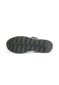 Black rubber shoe sole with deep diagonal grooves and textured grip pattern, brand logo near heel, shown against white background.