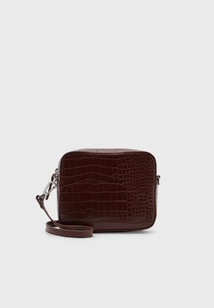 Mørkebrunt rektangulært crossbody taske med krokodille tekstur og justerbar strop på en ensfarvet lys baggrund.