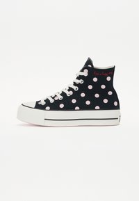Svarta höga sneakers i canvas med rosa prickar, vita snören och en tjock vit sula med en svart rand. Texten säger "ha en glad dag."