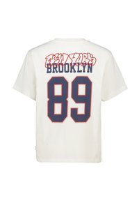 Valkoinen puuvillapaita, jossa on punainen ja laivastonsininen graafinen teksti: "BROOKLYN" ja "NEW YORK" suuren numeron "89" yläpuolella takana.