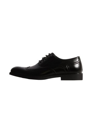 Chaussure Oxford noire en cuir à lacets, avec un bout brogue arrondi, présentée de profil sur fond blanc.