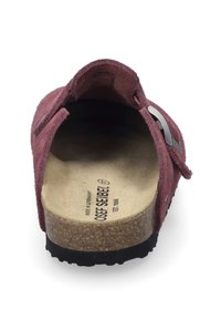 Rode suède klompen met een kurk voetbed, zwarte rubberen zool en een metalen accent. Zachte textuur en open achterkant ontwerp voor gemakkelijk aan- en uittrekken.