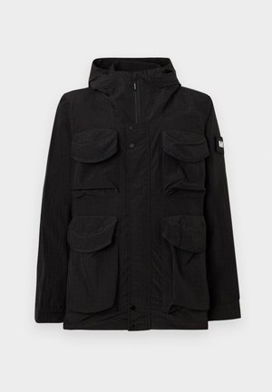 Veste noire à capuche avec quatre grandes poches à rabat à l'avant, fermeture éclair sur le devant avec boutons-pression, et un écusson logo sur la manche gauche.