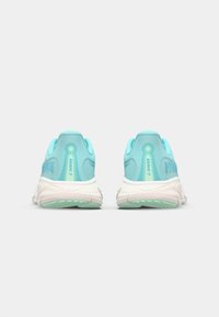 Light blue athletic shoes with a textured upper, cushioned white midsole, and green outsole. Features branding and heel loop for easy wear.