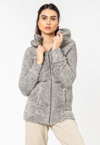 Gray fuzzy zip-up hoodie with a hood, featuring two front pockets and a soft texture. The design includes a patterned accent near the hem.