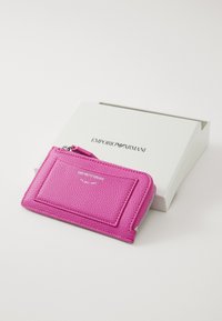 Porte-cartes en cuir rose vif avec surface texturée, fermeture éclair et poche avant. Comprend le logo Emporio Armani. Emballage en boîte.