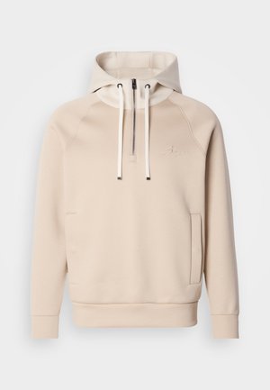 Sweatshirt à capuche beige avec une fermeture éclair quart, des poches avant et des poignets côtelés. Présente des détails brodés sur la poitrine et une texture douce.