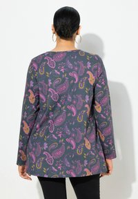 Langärmliges Oberteil aus dunkelgrauem Stoff, das mit einem lebhaften Paisleymuster in Pink, Gelb und Lila versehen ist. Abgerundeter Saum und lockere Passform.