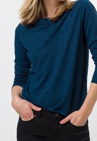 Turkoois, lange mouwen top met een gestructureerd patroon, met een ronde hals en een losse pasvorm, gecombineerd met zwarte broek.