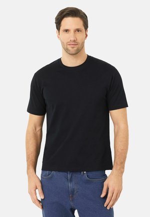 T-shirt en coton noir avec un col rond et des manches courtes, offrant une coupe décontractée et une texture lisse, associé à un jean en denim bleu.