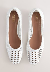 Witte gevlochten ballerina's met een open ontwerp, een gladde voering en een beige binnenkant. Heeft subtiele merkdetails in goud op de binnenzool.