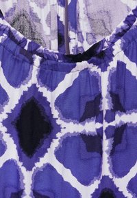 Lila-weiße, gemusterte Stoff mit glatter Textur; zeigt abstrakte Formen und ein gerafftes Ausschnittdetail.