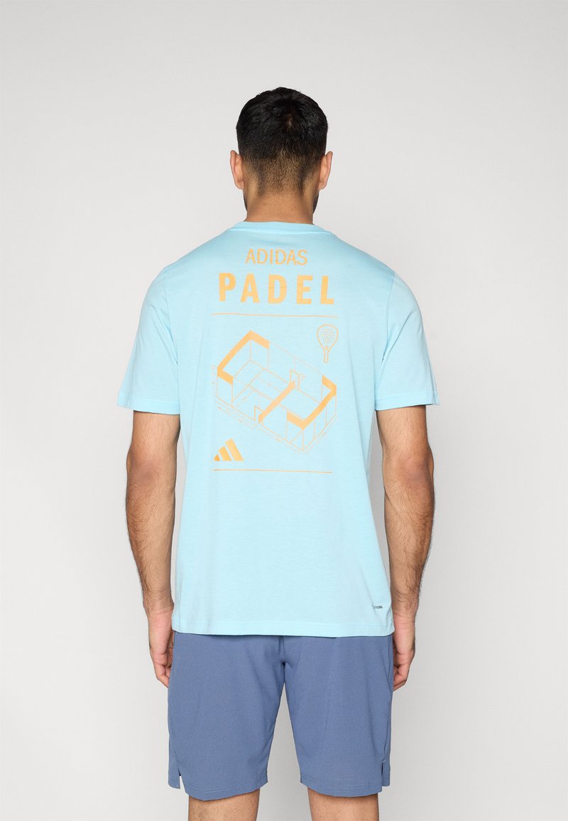 Φωτεινό γαλάζιο βαμβακερό t-shirt με πορτοκαλί κείμενο "ADIDAS PADEL" και γραφικό γήπεδου padel στην πλάτη. Κοντά μανίκια, στρογγυλή λαιμόκοψη.
