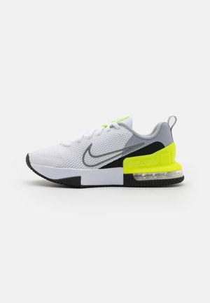 Nike athletic shoe featuring a white mesh upper, grey accents, black sole, and a vibrant yellow heel with air cushioning design.