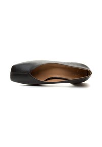 Zwarte leren schoen met een ronde neus, platte zool en open zijkanten. Het interieur heeft een tan kleurige voering met minimale stiksels.