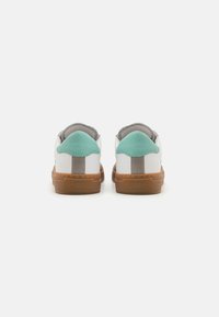 White sneakers with a turquoise heel, gray accents, and a brown rubber sole. Smooth leather upper with stitching detail. Simple design.