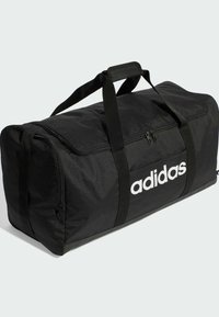 Black duffel bag with a zip closure, featuring a textured fabric and prominent white Adidas logo on the front. Two sturdy handles.